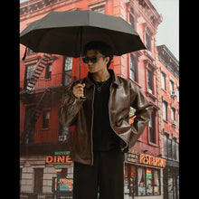 Person holding an umbrella in front of a city street backdrop with buildings and signs.